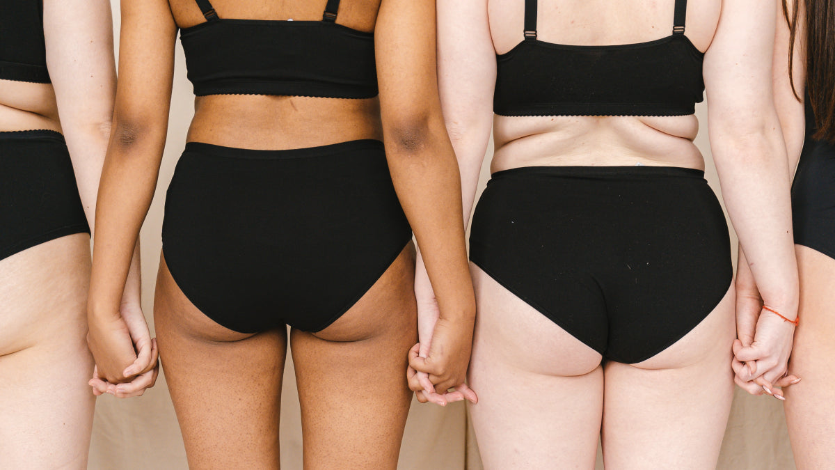 Four women from the back standing side-by-side and holding hands